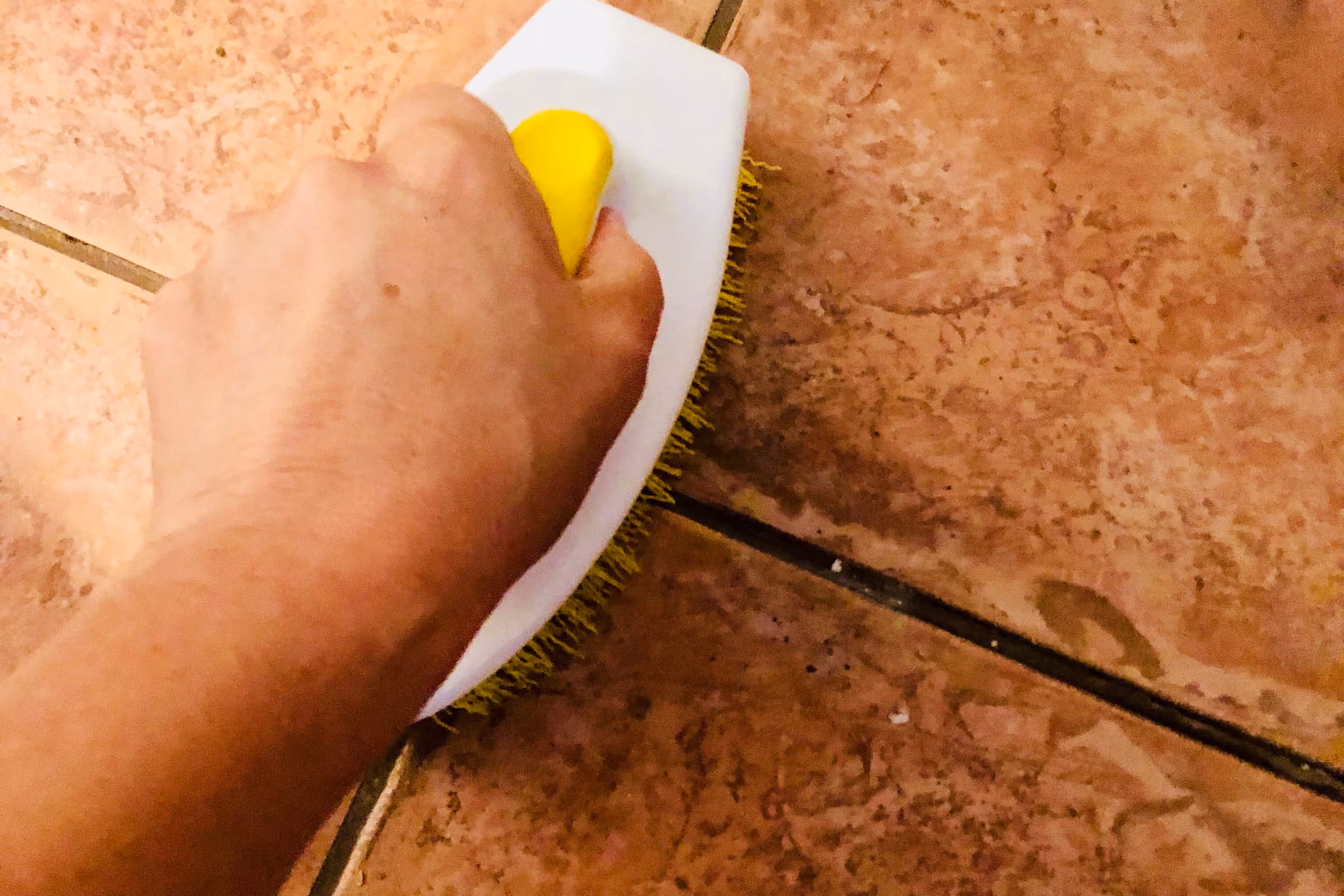 Limpiar suelo ennegrecido: frotando con estropajo una baldosa de barro